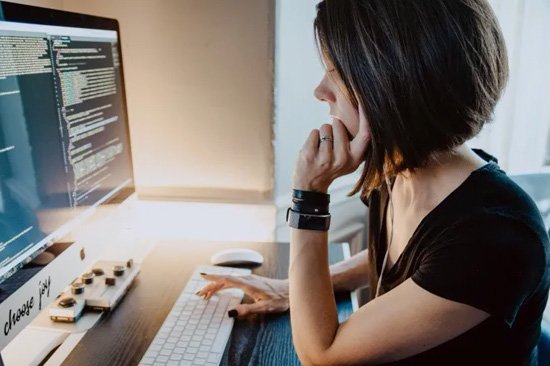 Mujer escribiendo código de programación en computadora